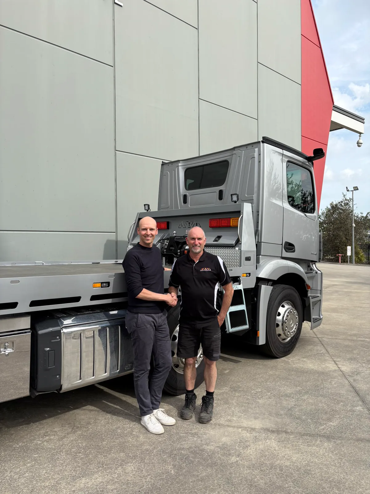 Stijn De Vriendt shaking hands with the outgoing owner of Customer Transport Equipment in front of a new CTE truck body at the factory.